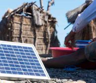 Small solar panel on the ground next to a hut