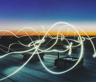Bright wavy lines travelling over a roof top at dusk