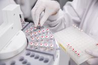 A hand wearing a nitrile glove loading an autosampler with vials