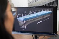 A person looking at a computer screen showing a simulation of wind turbine array