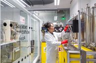 A technician wearing a lab coat, safety glasses and protective gloves adjusts dials on equipment in the Molecular Sciences Research Hub.