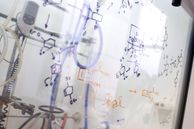 Synthesis pathways sketched on the front of a fume cupboard sash