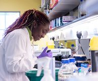 Researcher in lab coat holding a pipette