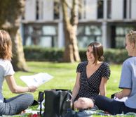 students sitting on the grass on campus