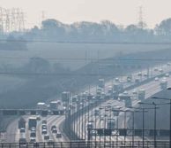 8 lanes of traffic on a motorway going through green hills