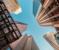 View looking up to blue sky through tall buildings