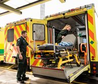 Two paramedics loading a bed on to an ambulance