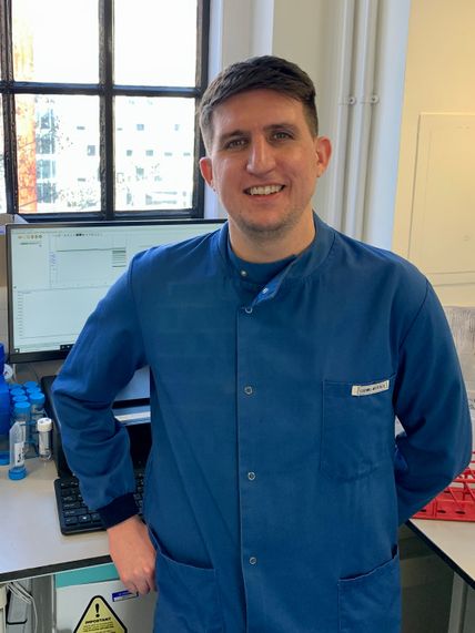 Dr Granger stands by a window in a lab in a blue lab coat