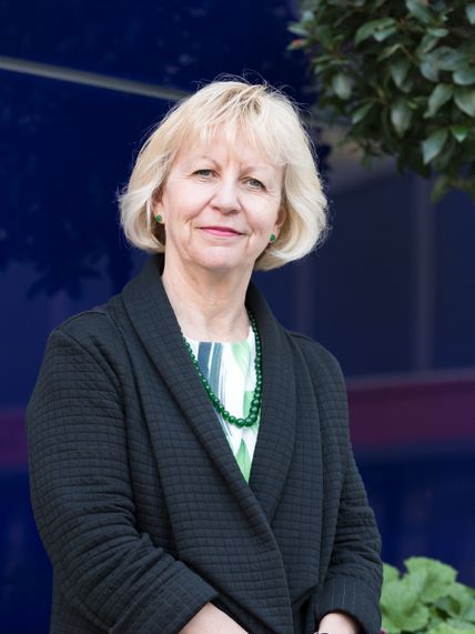 Portrait of Maggie stood in front of a blue building