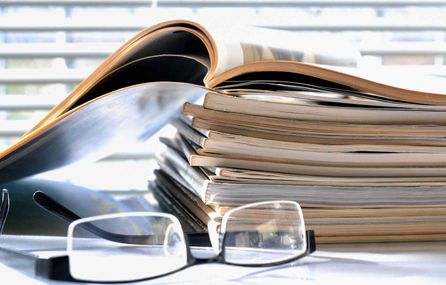 Glasses beside a pile of magazines