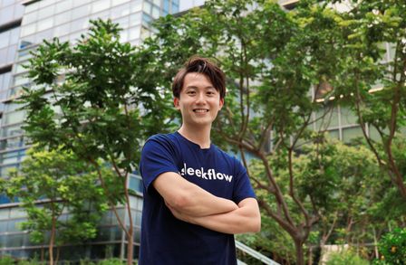 Henson Tsai standing with arms folded against backdrop of a building and trees