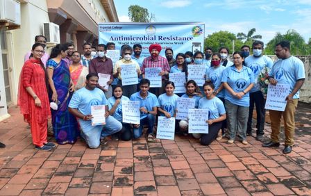 Participants of the AMR awareness week inaugural ceremony, crouch in front of a banner detailing the event.