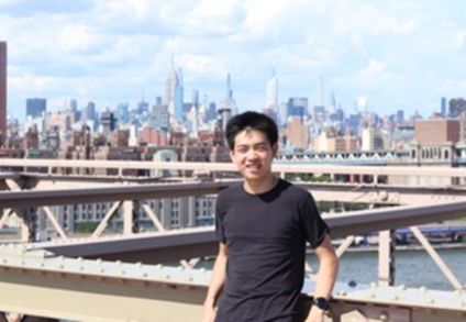 IROP student, George Zhang, standing in front of a New York city backdrop