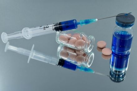 Syringe, ampoule and tablets on mirrored surface