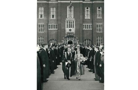 A photograpgh of the Queen Mother with Rector Sir Patrick Linstead on Charter Day 1957 with students lining the path from the Students' Union in Beit Quad