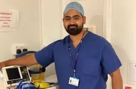Dr Karan Rajan wearing scrubs standing with medical equipment