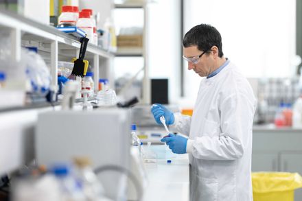 Man in a labcoat holding a pipette