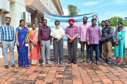 Participants of the AMR awareness week inaugural ceremony, stand in front of a banner detailing the event.