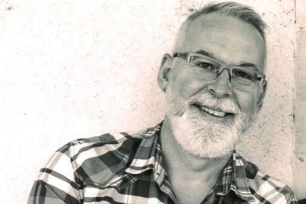 Black and white photo of Andy McAleer wearing checked shirt