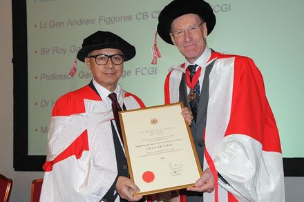 Hirak wearing a formal red/white gown and gap receiving the Fellowship award