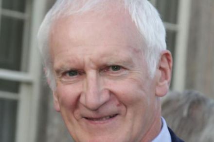 Headshot of John Beswick wearing red tie