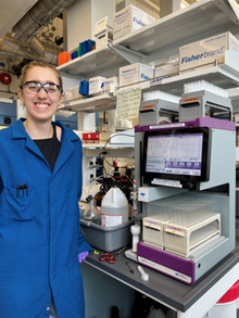 a student standing in front of a piece of equipment in the lab