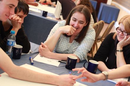 Group of phd student gathered together at a table working as a group