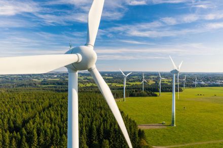 Figure shows wind turbine structures in a green field.