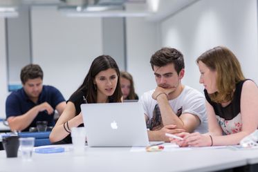 students discuss around a laptop