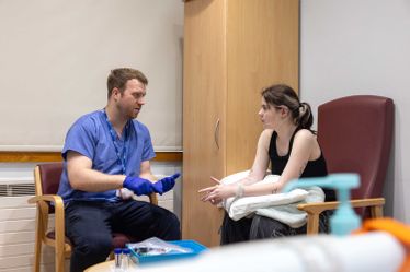 a doctor or trainee talks to a patient in a hospital room