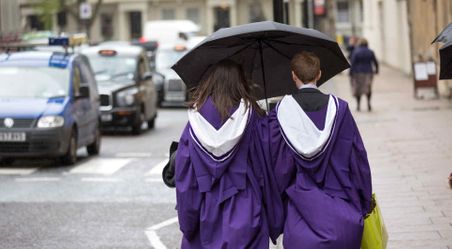 Two graduates wearing their graduation gowns