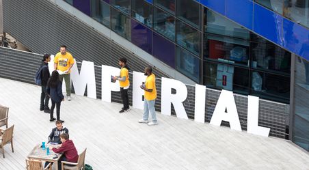 Tour guides gather in front of a large sign that says 'Imperial'.