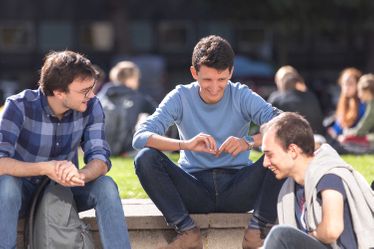 Three students chat on Queen's Lawn during Welcome Week.