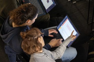 Bird's eye view of two students in the Dyson School of Engineering, working on one laptop together.