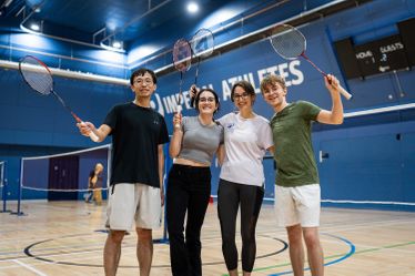 A group of students smiling with their badminton rackets