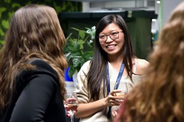 Woman smiles at someone as they chat at drinks reception