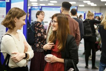 Two researchers smile whilst chatting at poster session