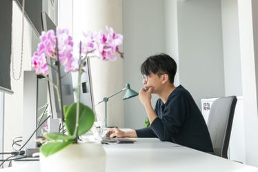 Student sits in front of laptop at their desk in bright clean office