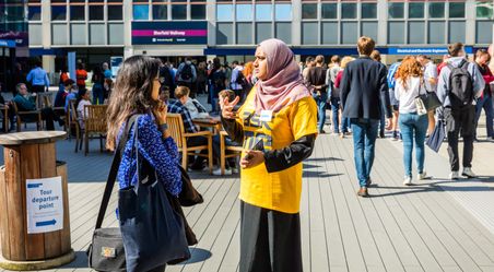 A volunteer speaks to visitors at an open day event