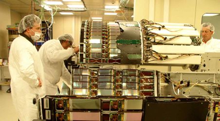 3 researchers wearing laboratory coats and masks working in a laboratory