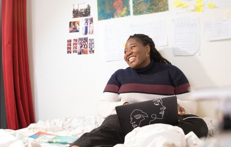 Student smiling on her laptop in halls