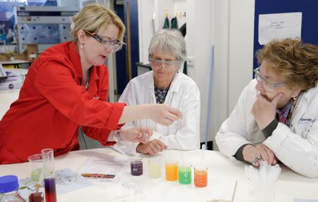 Donors get a demonstration in the lab using coloured liquids in beakers