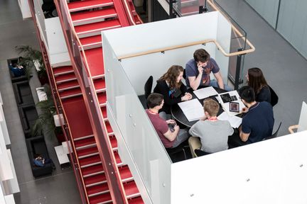 A team sits around a table in the ICTEM Building Hammersmith to discuss their work