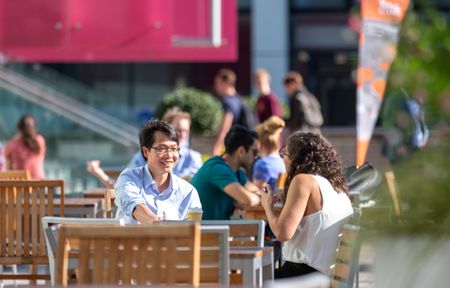 Students talking on outdoor seating in the sun