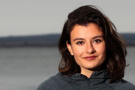 Portrait of Anahita Laverack, one of the Entrepreneurs' Pledgers, smiling against a backdrop of open water