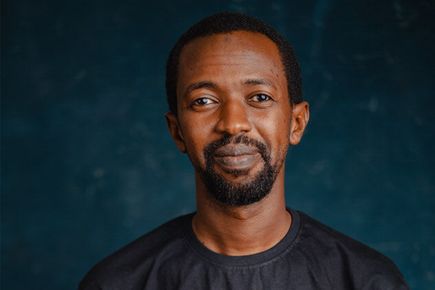 Portrait of Anas Yazid, one of the Entrepreneur's Pledgers, smiling at the camera against a dark blue backdrop