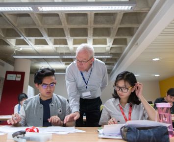 two students at a workshop being supported by a member of staff