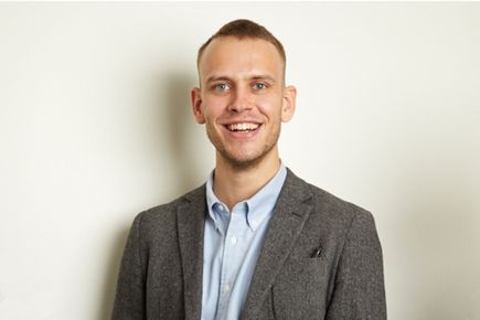 Henrik Hagemann smiles at the camera, against a white background