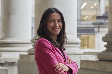 Dr Theodora Kalentzi smiles at the camera, against a background with stone pillars