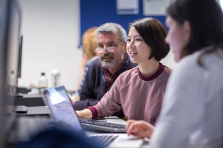 Two students and a lecturer work at a computer